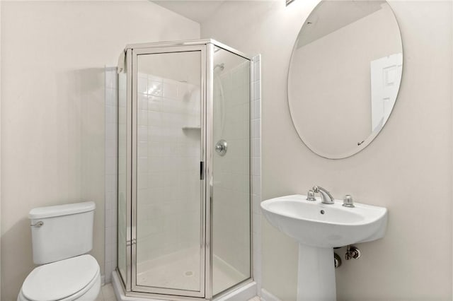 bathroom featuring toilet and a shower with shower door