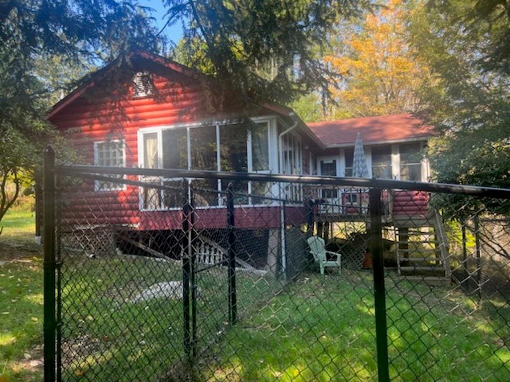 rear view of house featuring a lawn, a wooden deck, and a sunroom