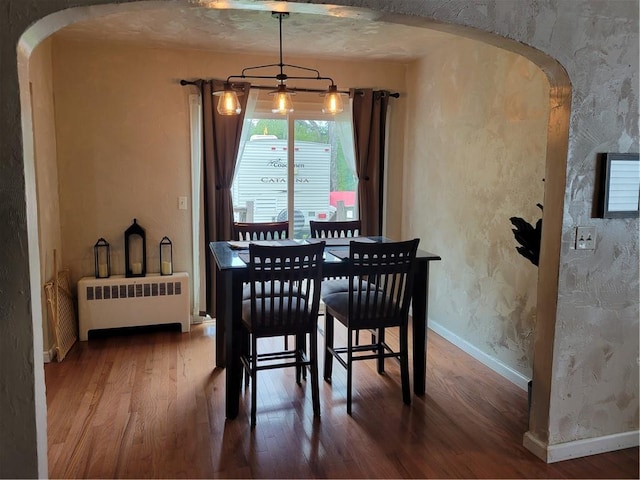 dining room featuring hardwood / wood-style flooring, a notable chandelier, and radiator