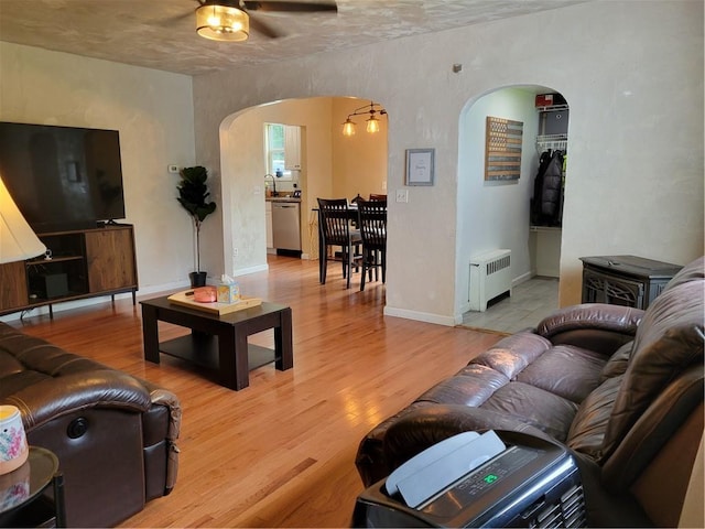 living room featuring ceiling fan, light hardwood / wood-style floors, and radiator