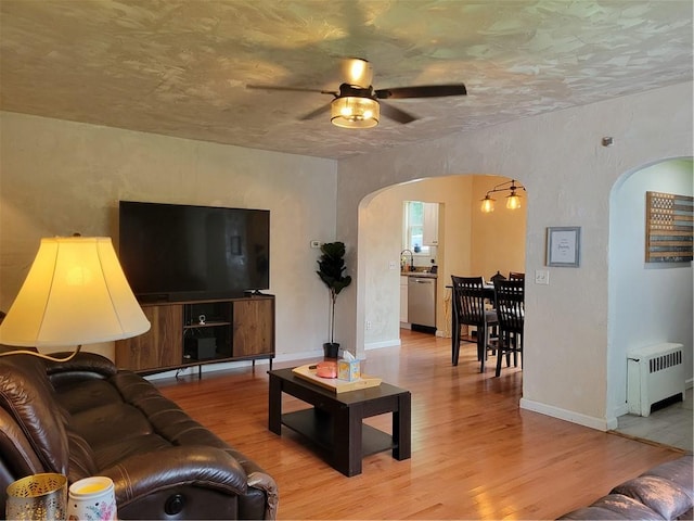 living room featuring ceiling fan, light hardwood / wood-style floors, and radiator