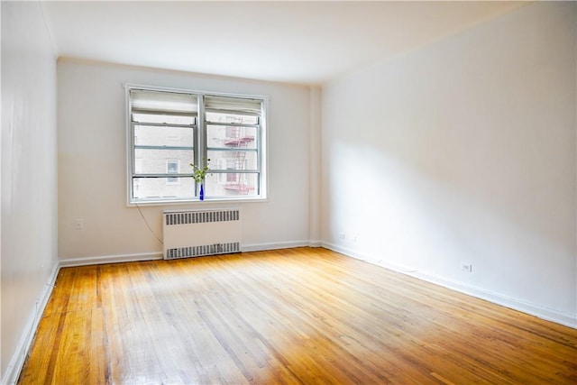 spare room featuring radiator and light hardwood / wood-style flooring