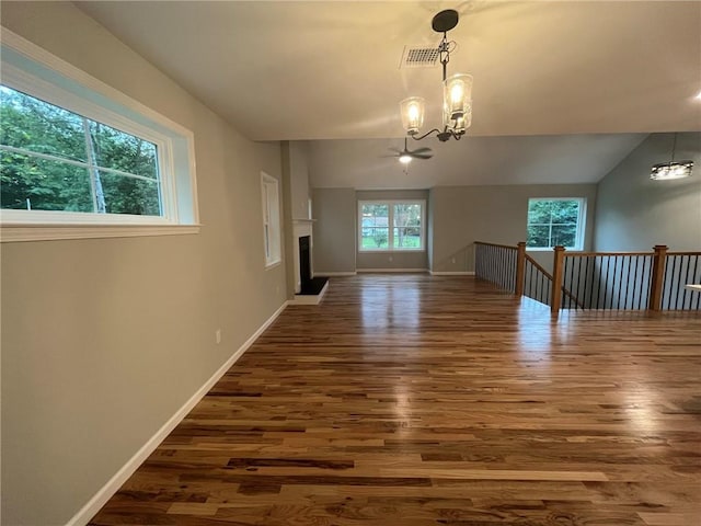 interior space featuring ceiling fan with notable chandelier, dark hardwood / wood-style flooring, and lofted ceiling