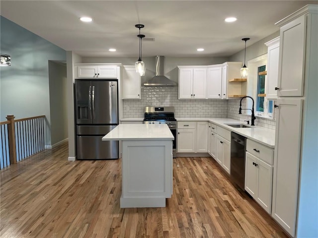 kitchen with sink, hanging light fixtures, wall chimney exhaust hood, light wood-type flooring, and stainless steel appliances