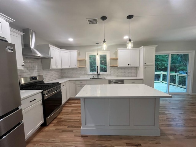 kitchen featuring white cabinets, stainless steel appliances, and wall chimney range hood