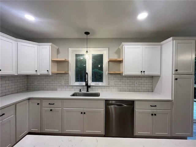 kitchen featuring white cabinets, sink, hanging light fixtures, decorative backsplash, and light stone countertops