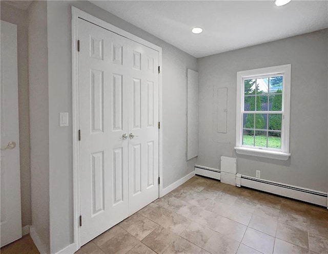 unfurnished bedroom with baseboard heating and a closet