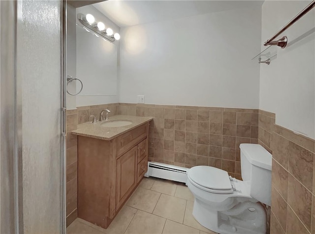 bathroom featuring tile patterned flooring, a baseboard heating unit, toilet, vanity, and tile walls
