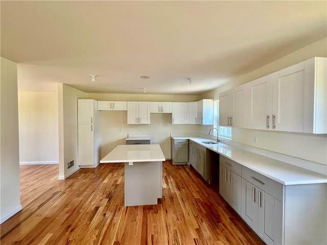 kitchen featuring sink, a kitchen island, gray cabinets, white cabinets, and light wood-type flooring