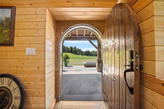 entryway featuring wooden ceiling, wooden walls, and light tile patterned flooring