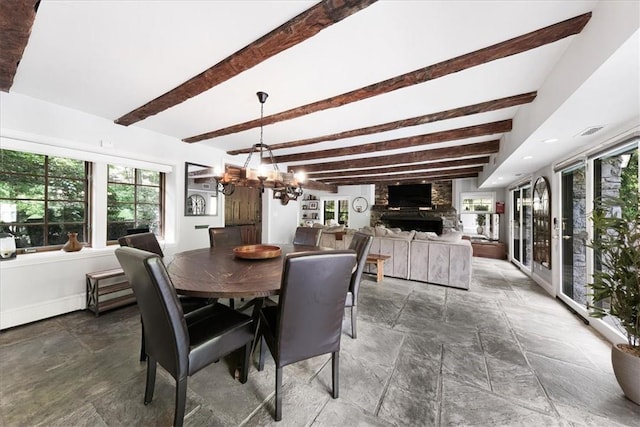 dining area with a large fireplace, beamed ceiling, and a notable chandelier