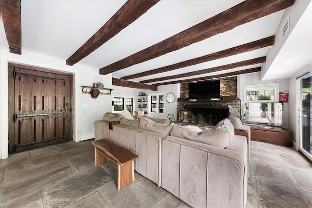 living room with beam ceiling and a stone fireplace