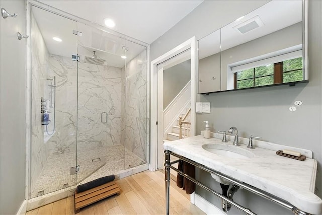 bathroom with vanity, a shower with shower door, and wood-type flooring