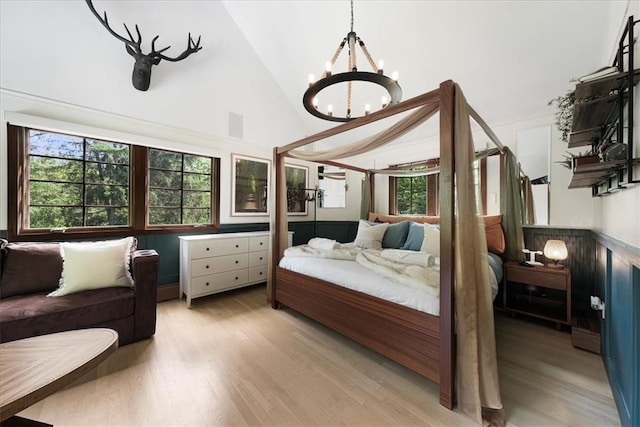 bedroom featuring multiple windows, high vaulted ceiling, a chandelier, and light wood-type flooring