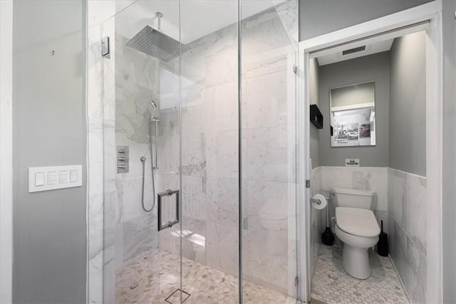 bathroom featuring walk in shower, toilet, and tile walls