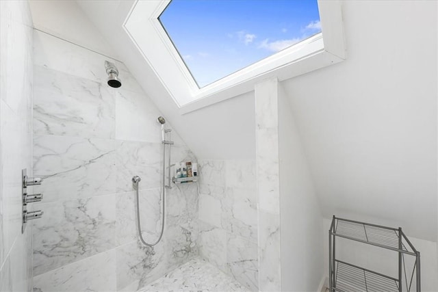 bathroom featuring a tile shower and lofted ceiling with skylight