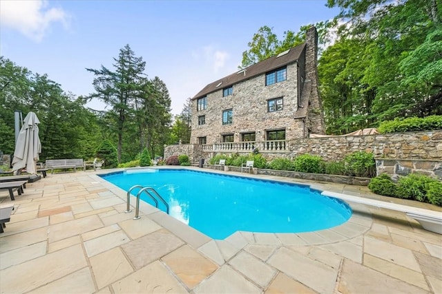 view of swimming pool with a diving board and a patio area