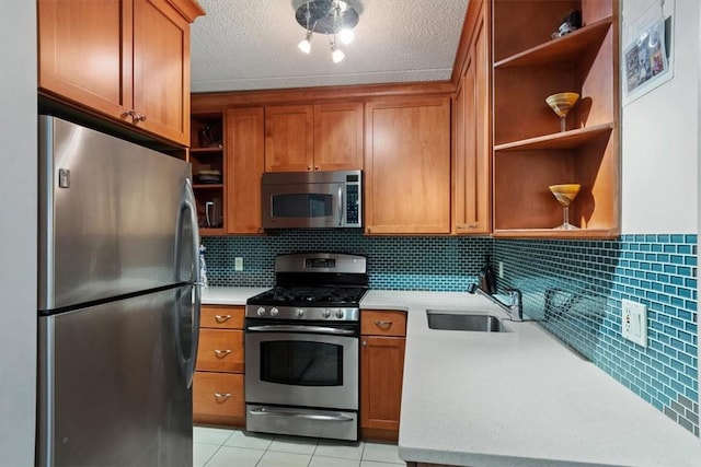 kitchen with appliances with stainless steel finishes, tasteful backsplash, a textured ceiling, sink, and light tile patterned flooring