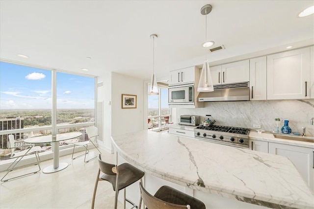 kitchen featuring white cabinets, decorative light fixtures, stainless steel appliances, and a wealth of natural light