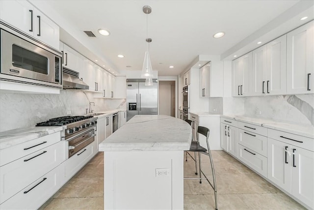 kitchen featuring built in appliances, white cabinets, a kitchen island, and decorative light fixtures