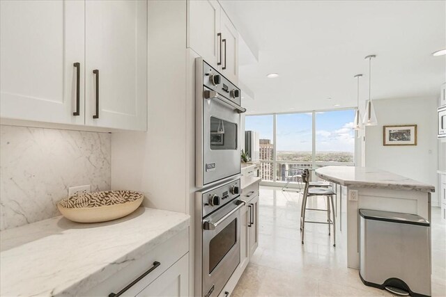 1 Renaissance Sq Unit Ph2Bc, White Plains, NY 10601 - kitchen with stainless steel oven, tasteful backsplash, expansive windows, white cabinets, and recessed lighting