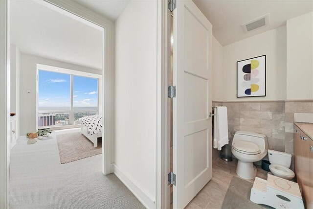 1 Renaissance Sq Unit Ph2Bc, White Plains, NY 10601 - bathroom featuring toilet, vanity, tile walls, and wainscoting