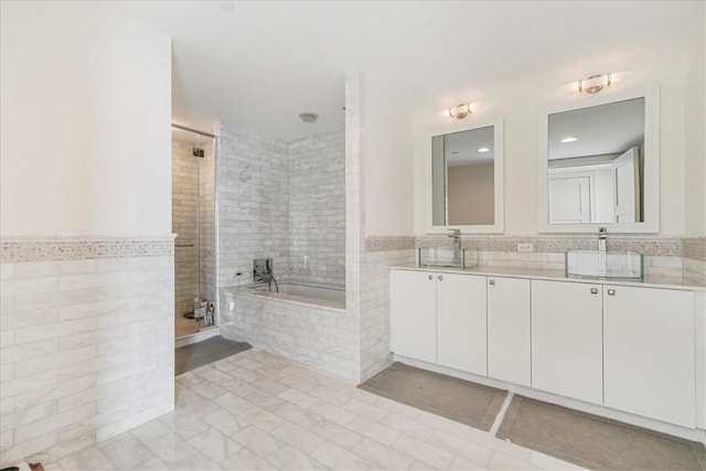 1 Renaissance Sq Unit Ph2Bc, White Plains, NY 10601 - bathroom featuring tile walls, double vanity, tiled shower, a garden tub, and wainscoting