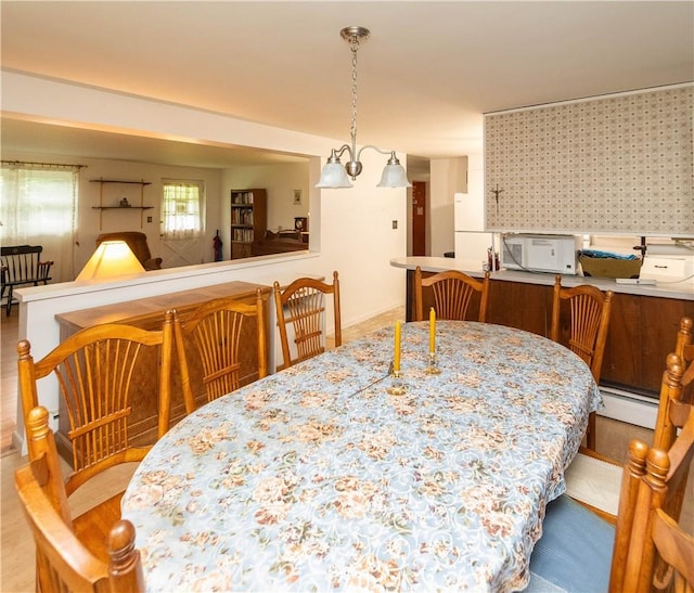 dining area with a notable chandelier, light wood-type flooring, and a baseboard radiator