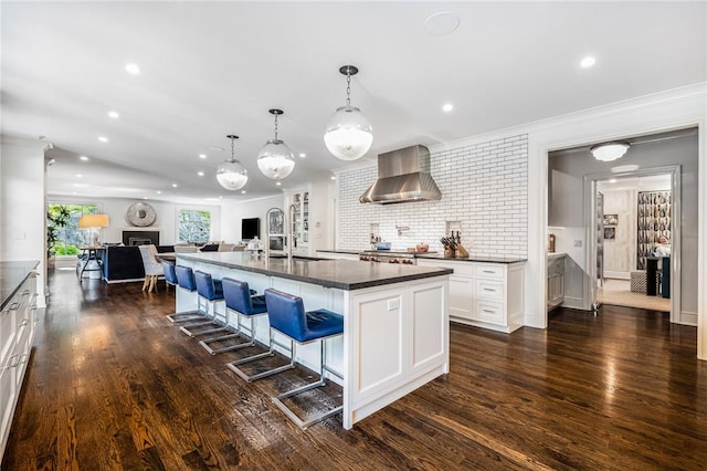 kitchen with dark hardwood / wood-style floors, white cabinetry, a spacious island, and wall chimney range hood