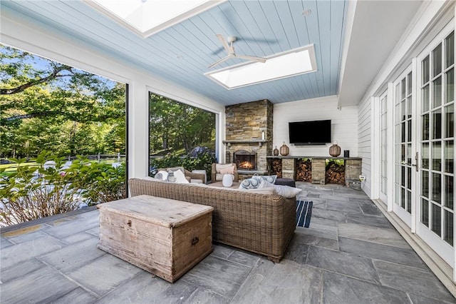 sunroom / solarium featuring an outdoor stone fireplace, wood ceiling, and a skylight