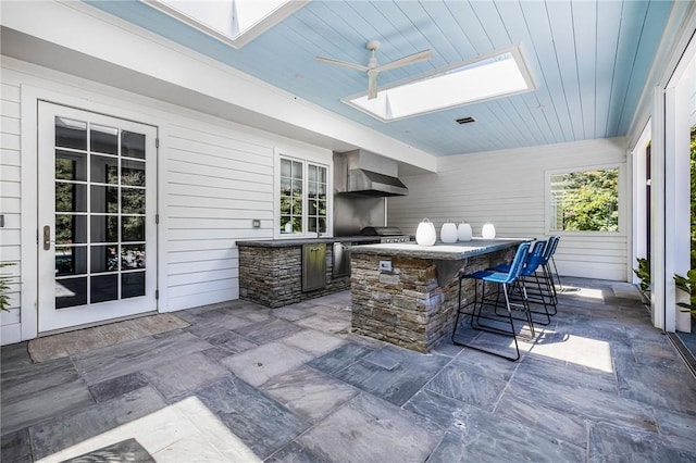 view of patio with area for grilling, ceiling fan, and an outdoor bar