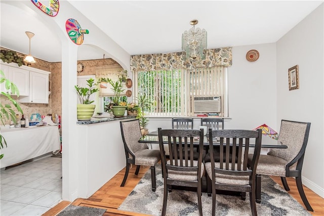 dining space featuring light hardwood / wood-style flooring, cooling unit, and a notable chandelier