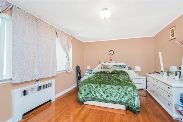 bedroom featuring radiator heating unit, light hardwood / wood-style floors, and ornamental molding