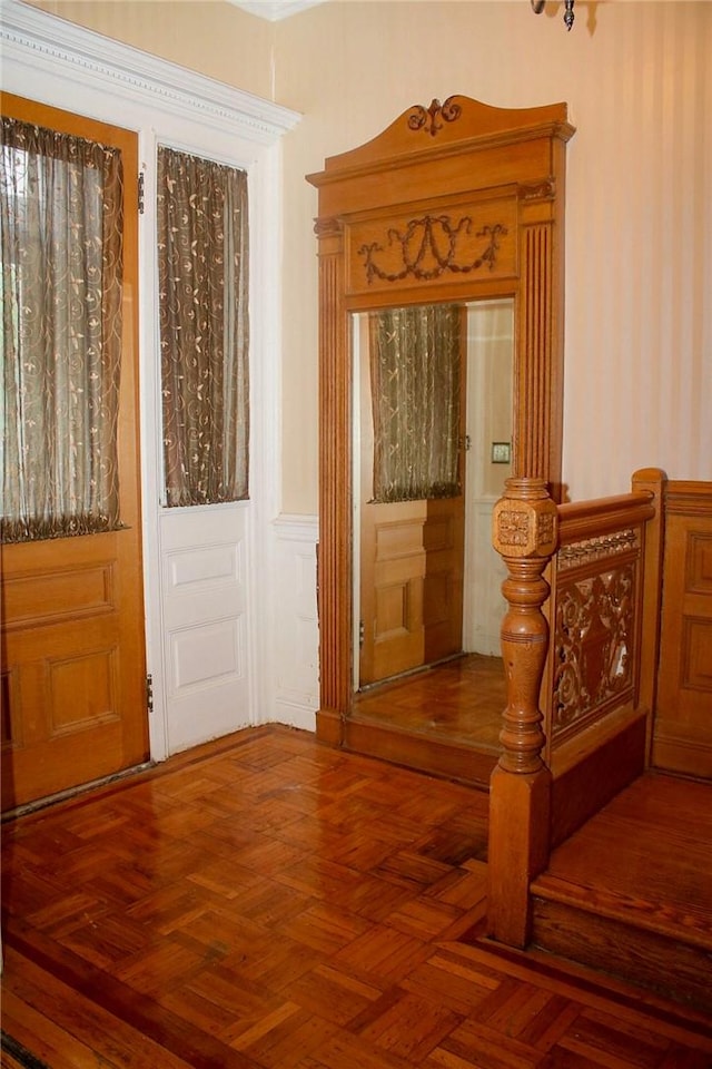 entryway with dark parquet floors and crown molding