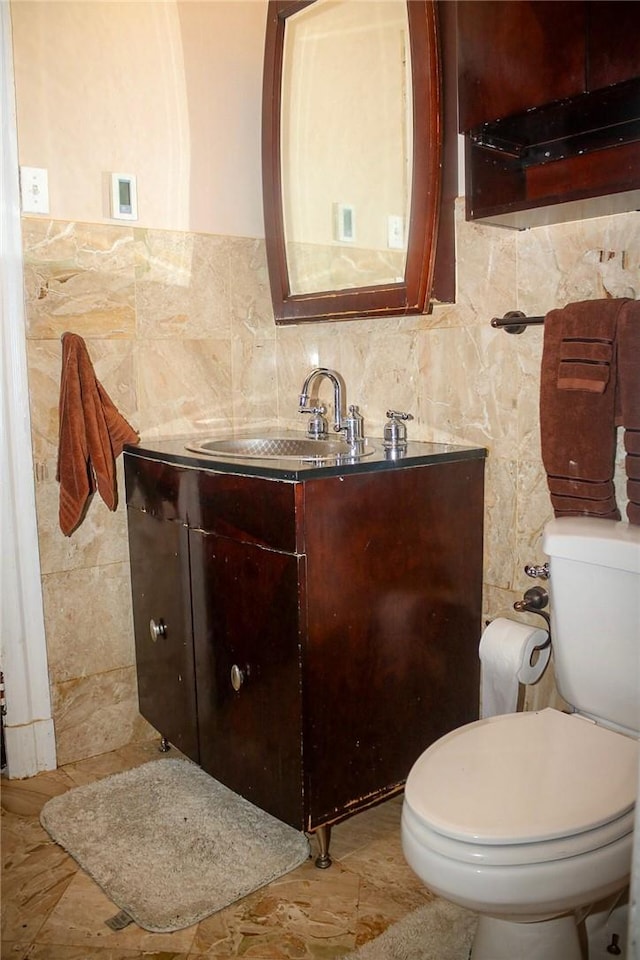 bathroom featuring vanity, toilet, and tile walls