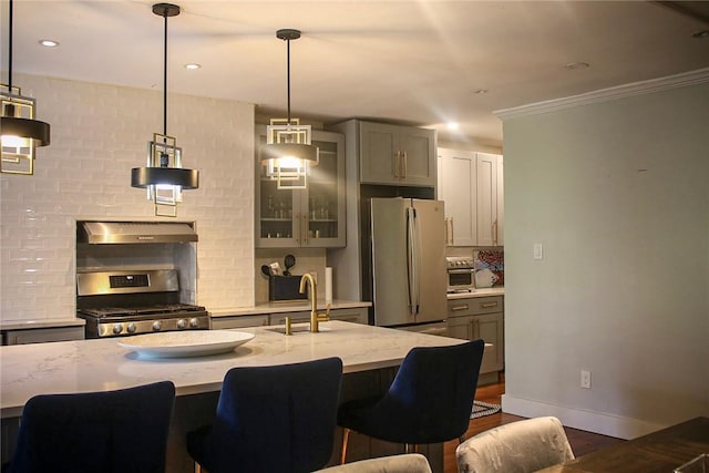 kitchen with light stone countertops, sink, backsplash, decorative light fixtures, and appliances with stainless steel finishes