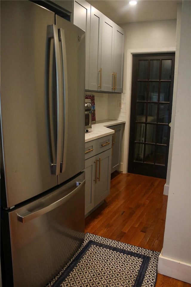 kitchen with tasteful backsplash, stainless steel refrigerator, gray cabinetry, and dark hardwood / wood-style floors