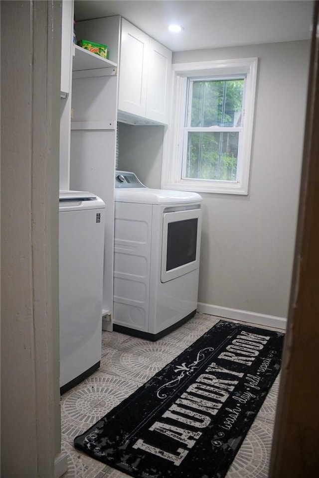 clothes washing area with cabinets and separate washer and dryer