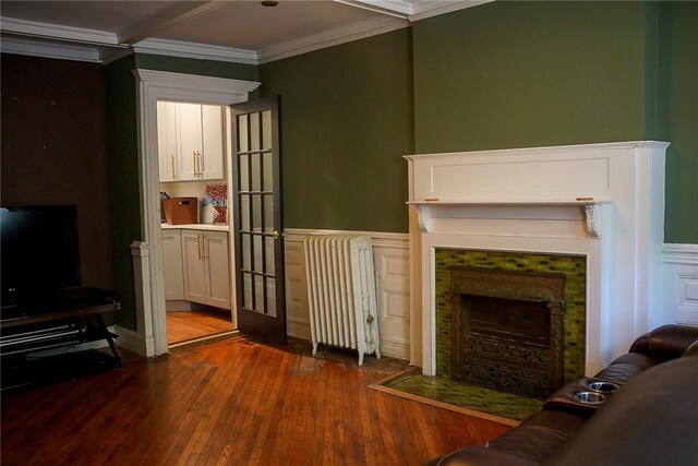 living room with dark hardwood / wood-style flooring, radiator, and ornamental molding