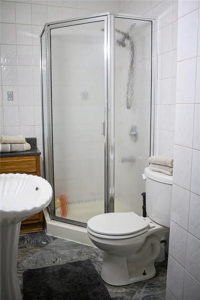 bathroom featuring toilet, an enclosed shower, and tile walls