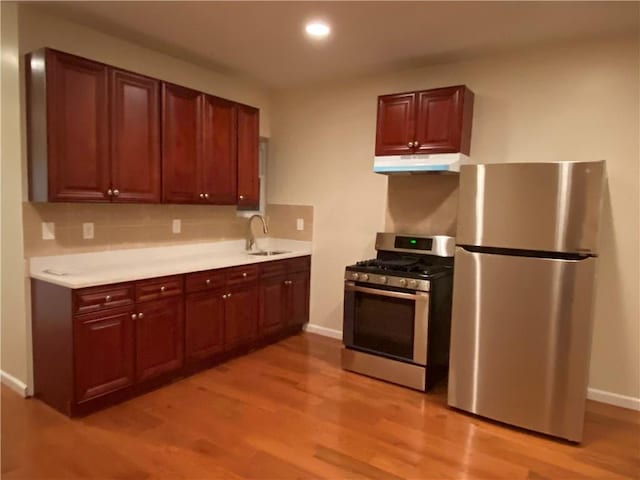 kitchen with decorative backsplash, sink, light wood-type flooring, and stainless steel appliances