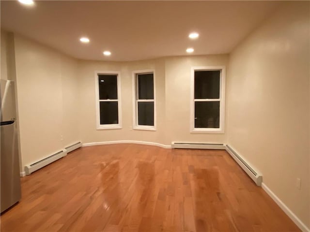 spare room with light wood-type flooring and a baseboard heating unit