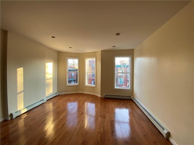 unfurnished room with a baseboard radiator and wood-type flooring