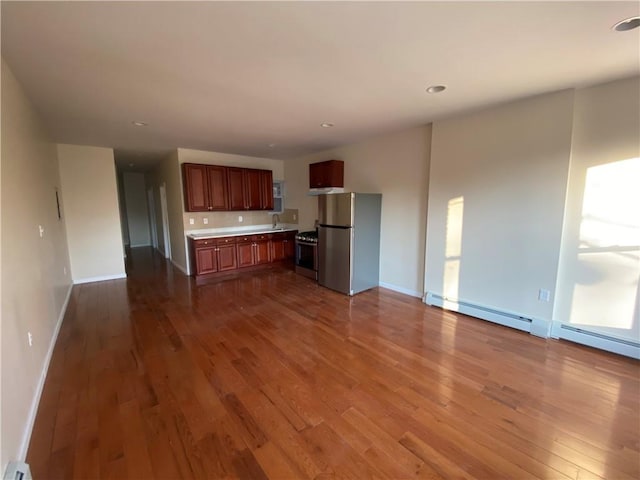 kitchen with wood-type flooring, sink, appliances with stainless steel finishes, and a baseboard heating unit