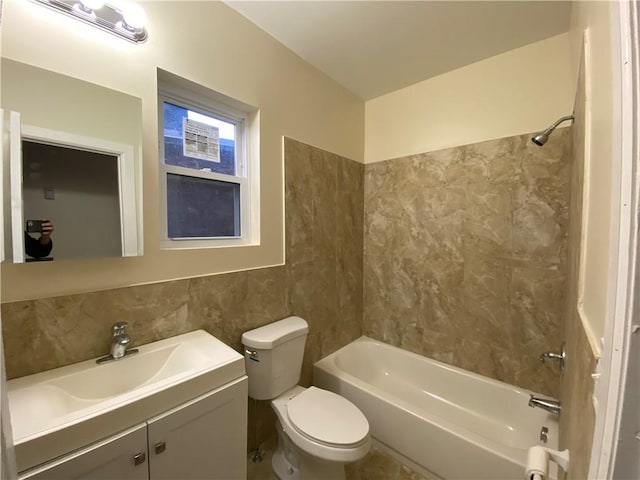 full bathroom featuring vanity, toilet, tiled shower / bath, and tile walls