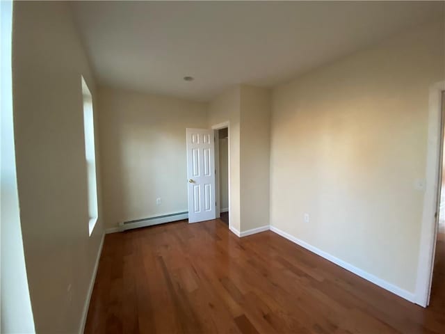 spare room with dark hardwood / wood-style flooring and a baseboard radiator