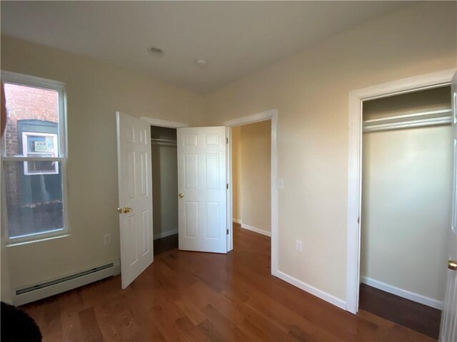 unfurnished bedroom featuring dark hardwood / wood-style floors, a closet, and a baseboard heating unit