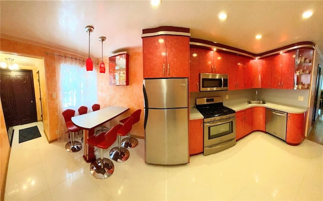 kitchen with pendant lighting, sink, light tile patterned floors, ornamental molding, and stainless steel appliances