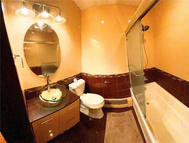 bathroom with an enclosed shower, vanity, toilet, and tile walls