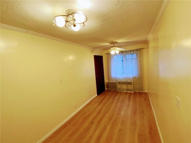 empty room with ceiling fan with notable chandelier, a textured ceiling, hardwood / wood-style flooring, and ornamental molding